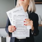 Empresária segura e analisa documentos tributários em um escritório.