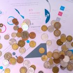 Moedas sobre documentos financeiros com gráficos e tabelas.