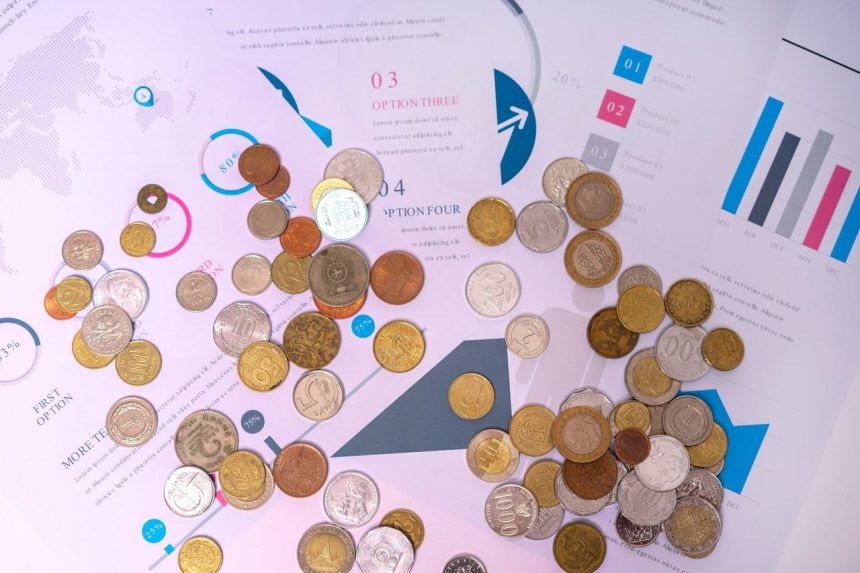 Moedas sobre documentos financeiros com gráficos e tabelas.